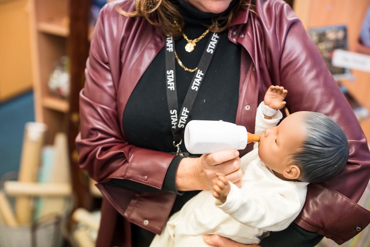 Member of staff feeding a baby doll