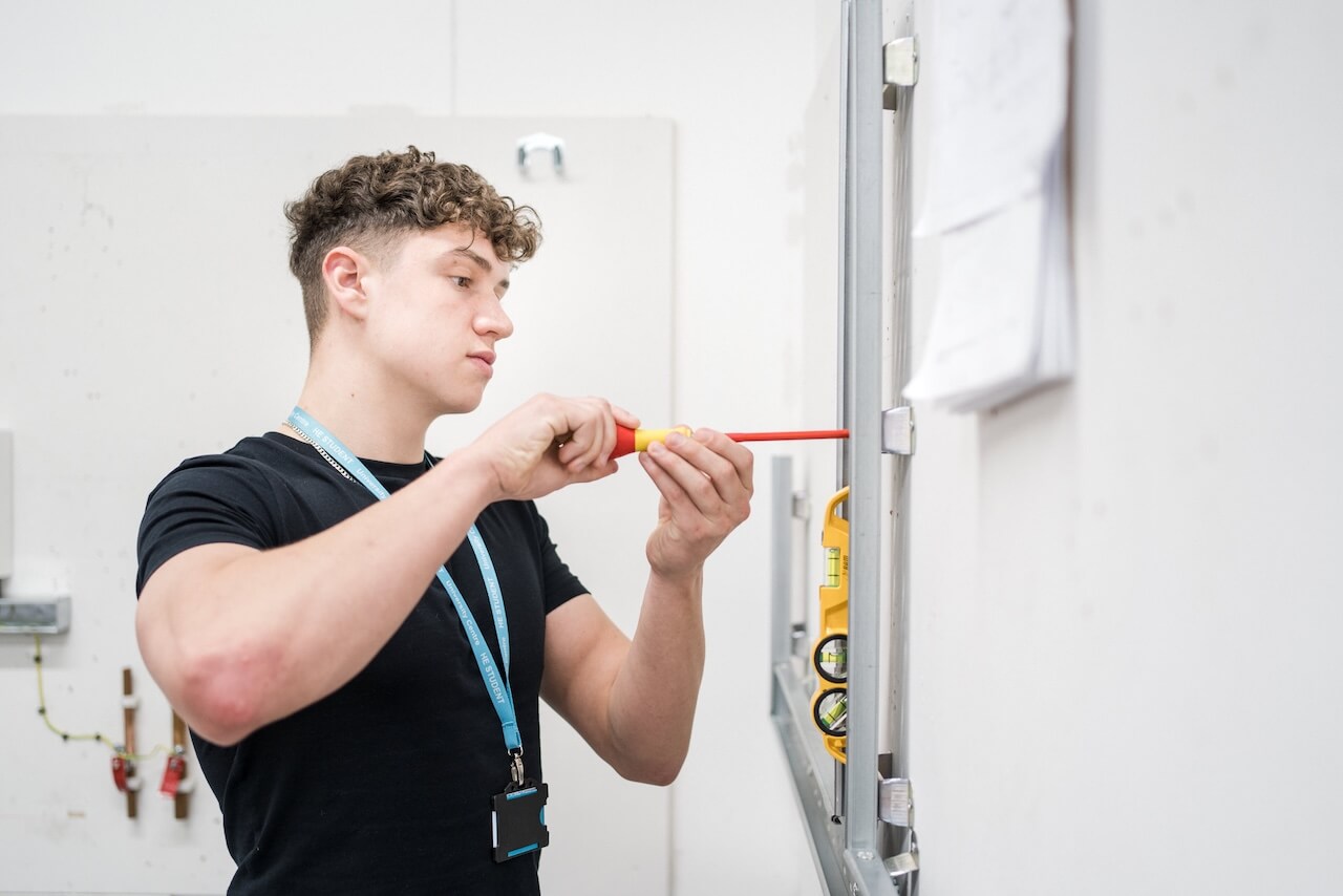 Electrical student screwing something into a wall fitting