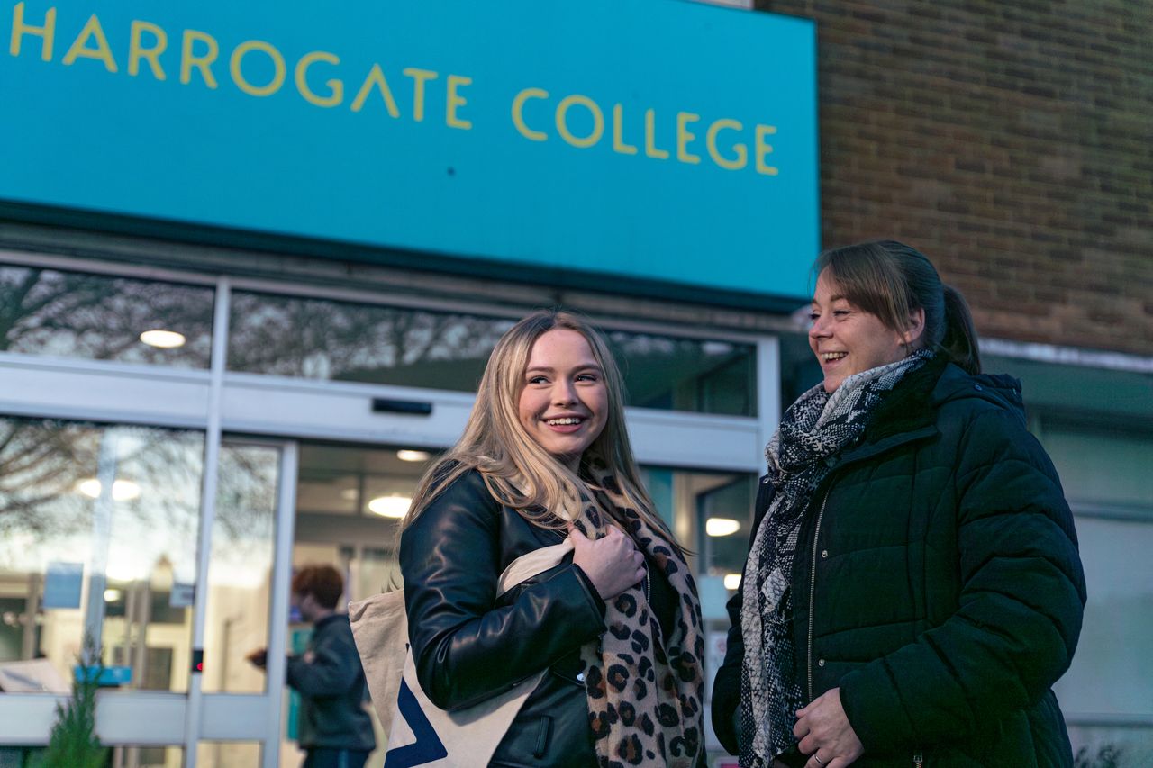 Two students outside of the college entrance on a late autumn afternoon/ early evening